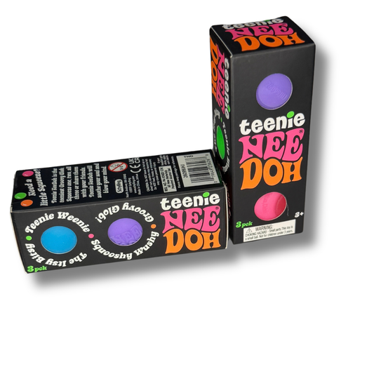 Two black retail boxes of Teenie Nee Doh makeup, one standing upright and one lying on its side, showing colorful circular color windows and the brand name in bold pink, orange, and white lettering.