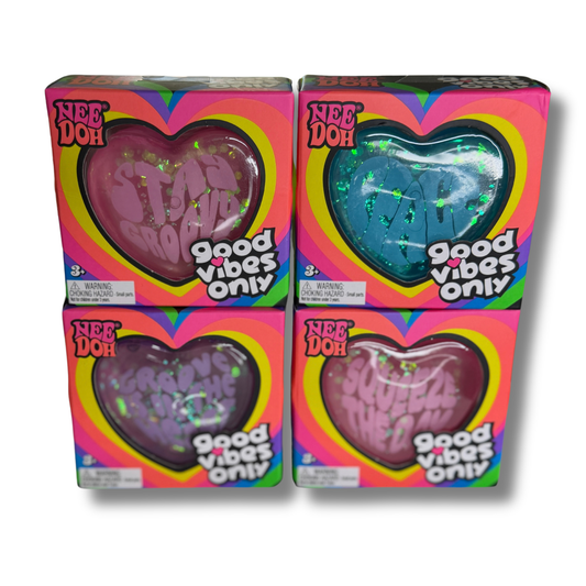 Four boxes of Nee Doh 'Good Vibes Only' slime arranged in a 2x2 grid on a white background. The boxes feature colorful rainbow borders and large heart-shaped windows showing the different colored slime inside: pink, blue, purple, and mauve.
