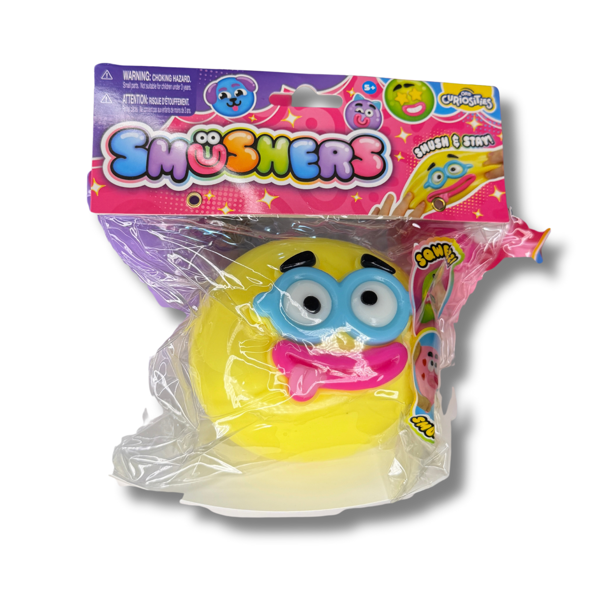 A packaged yellow squishy toy with a blue eyeglass face and pink tongue, sealed in clear plastic with a colorful 'Smushers' branded retail header card.